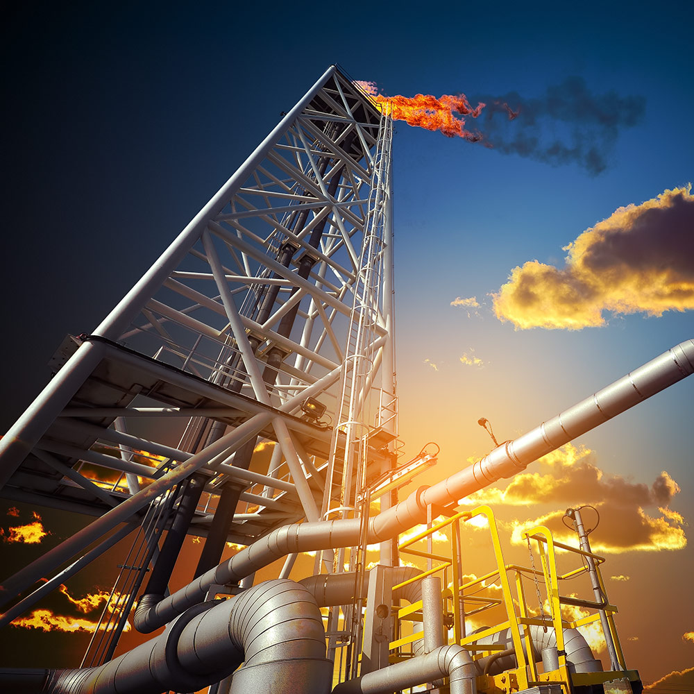 A plated oil extraction rig, with flames at the top against the sunset sky