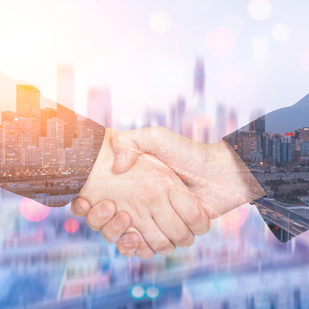 Semi-transparent image of a handshake on top of a big city skyline in the sunset