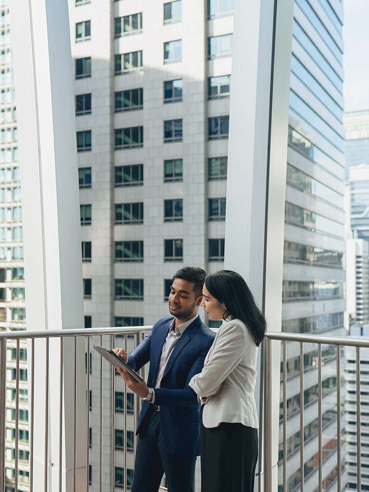 Two real estate agents checking a property features in a tablet screen on the balcony of a high floor apartment